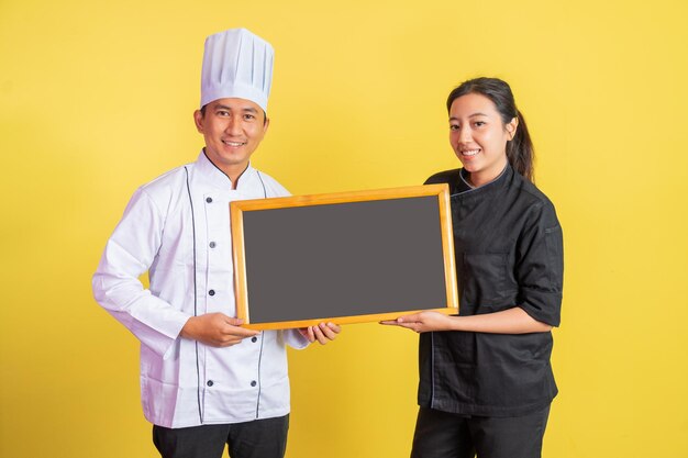 Chef masculino com chef feminino mostrando uma lousa em branco