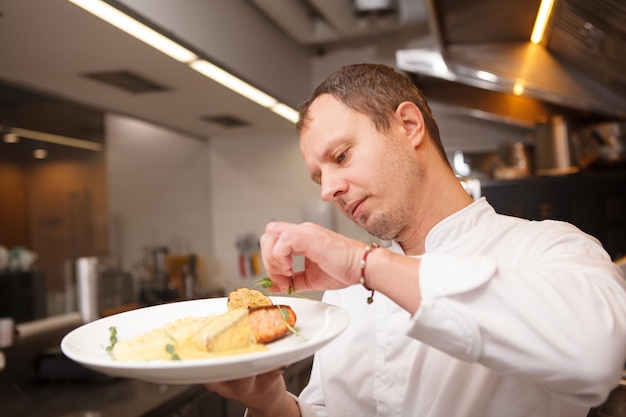 Chef masculino decorando salmão frito, trabalhando no restaurante