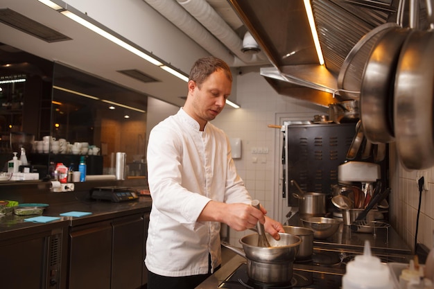 Chef masculino derretendo manteiga, cozinhando na cozinha do restaurante, copiando espaço