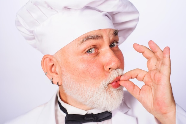 Chef masculino em uniforme branco e gravata borboleta com sinal perfeito cozinheiro com gesto de aprovação de gosto barbudo