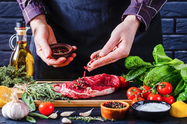 Chef masculino está rociando pimienta en bistec