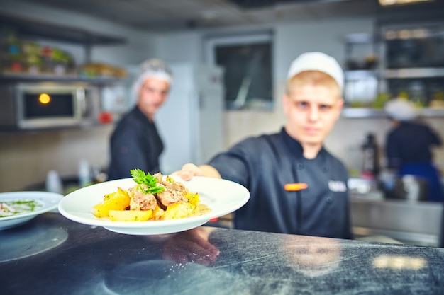 Foto chef masculino feliz cozinhando comida na cozinha do restaurante