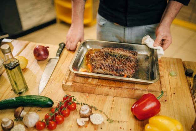Foto chef masculino na frigideira com carne assada e vetables