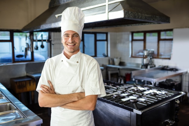 Foto chef masculino de pie con los brazos cruzados en la cocina