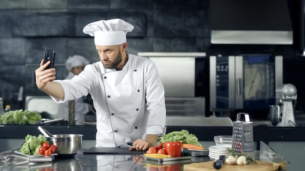 Chef masculino tomando foto selfie en la cocina Chef profesional con cuchillo