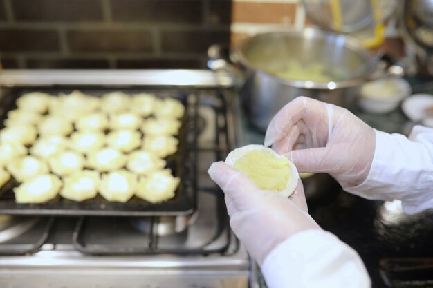 Chef masculino usa ingredientes para preparar produtos de farinha na mesa da cozinha