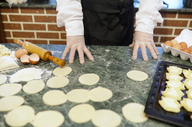 Chef masculino utiliza ingredientes para preparar productos de harina en la mesa de la cocina