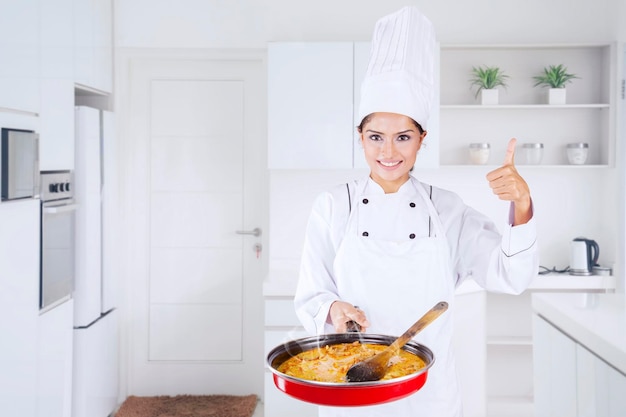 El chef muestra el pulgar hacia arriba y la comida sabrosa en la cocina