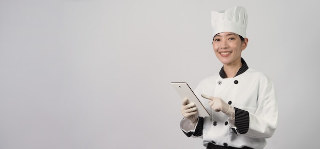 Chef mujer asiática sosteniendo un teléfono inteligente o tableta digital y recibió un pedido de comida de la tienda en línea