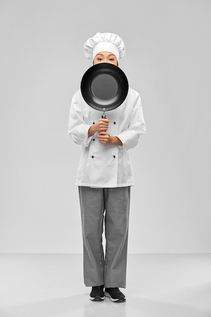 chef mujer asomando desde detrás de la sartén