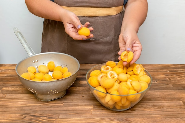 Chef mujer caucásica pelando frutas de albaricoques en un tazón, preparándose para hacer mermelada en la cocina de casa en verano otoño, cocina en línea, instrucción de recetas.