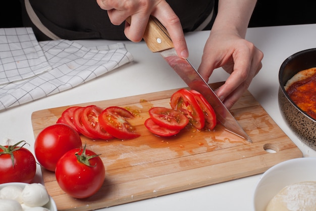 Chef mujer corta los tomates.