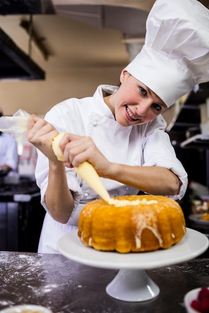 Foto chef mujer piping un pastel en la cocina