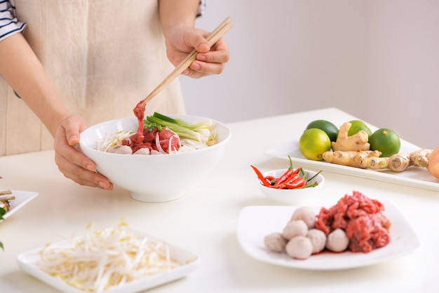 Chef mujer preparar sopa tradicional vietnamita Pho bo con hierbas, carne, fideos de arroz