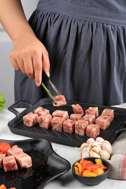 Chef mujer que prepara carne de res en cubos Wagyu de primera calidad o Saikoro, carne de mármol cortada en cubos para parrilla, tepanyaki o Yakiniku. Enfoque seleccionado