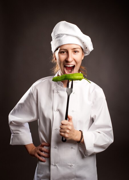 Chef mujer sosteniendo un pimiento verde con un tenedor