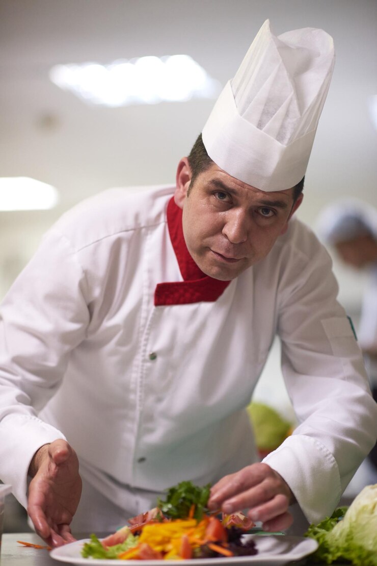 Foto chef na cozinha do hotel preparando e decorando comida, deliciosos legumes e jantar de carne