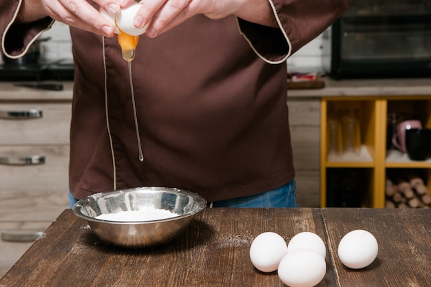 Chef na cozinha quebrando ovo no prato