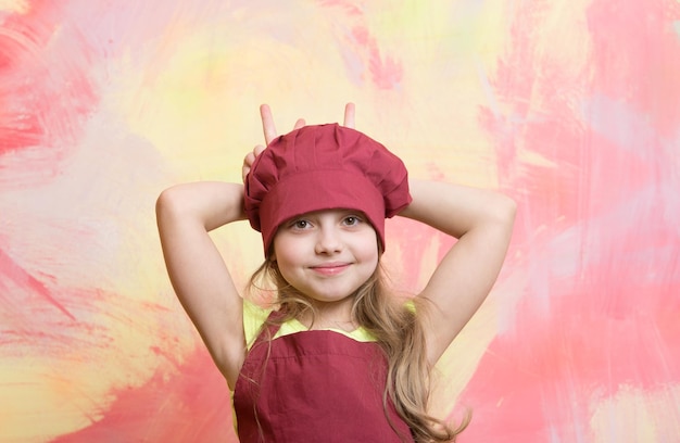 Chef niño o niña feliz cocinar en sombrero de chef rojo y delantal sobre fondo abstracto colorido cocinar y comer
