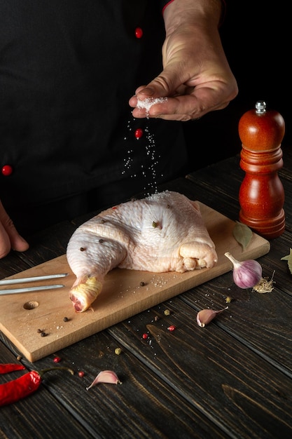 Chef o cocinero agrega sal a la pierna de pollo