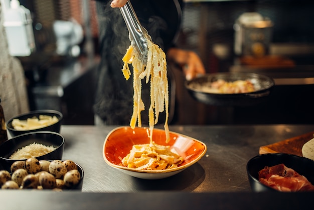 Chef con pan cocinar pasta en mesa de madera. Adorne para bistec, preparación de alimentos en la cocina