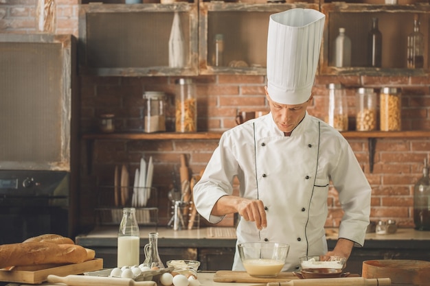 Chef de panadería cocinar hornear en la cocina añadiendo harina profesional