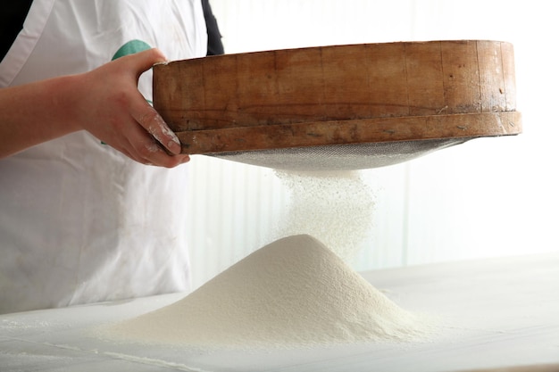 Chef peneirando farinha para fazer pão