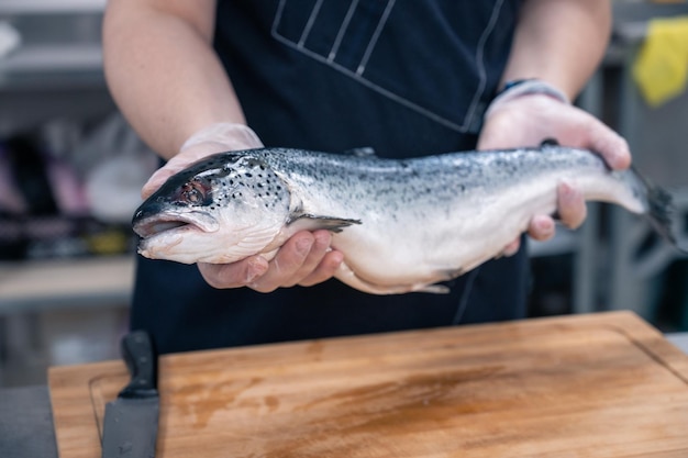 Chef con un pescado salmón en la cocina.