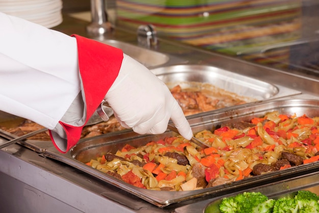 Chef de pie detrás de la estación de servicio de almuerzo completo