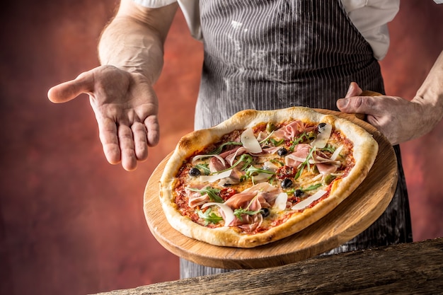 Chef y pizza. Chef ofreciendo pizza en hotel o restaurante.