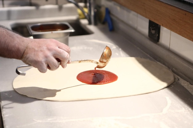 El chef de pizza puso salsa en la base de una cocina comercial