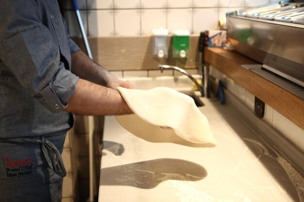 El chef de pizza puso salsa en la base de una cocina comercial