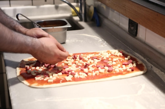 El chef de pizza puso salsa en la base de una cocina comercial