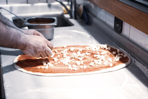 El chef de pizza puso salsa en la base de una cocina comercial