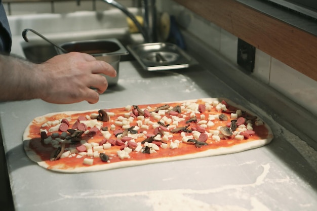 El chef de pizza puso salsa en la base de una cocina comercial