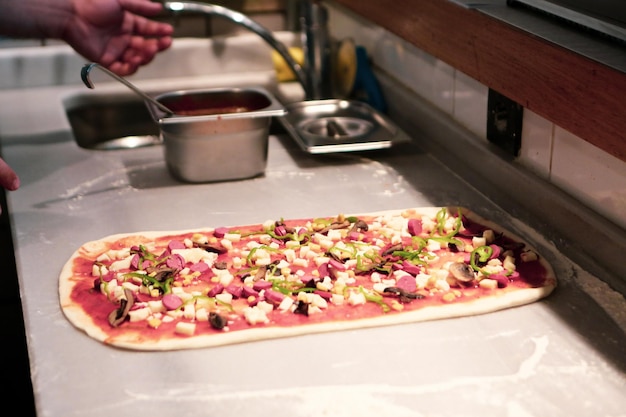 Foto el chef de pizza puso salsa en la base de una cocina comercial