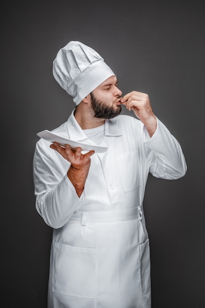 Chef con plato vacío besando los dedos