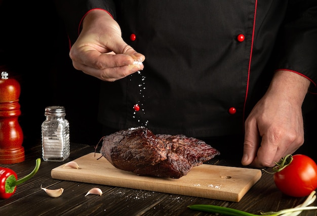 Chef polvilha a carne assada com sal o conceito de cozinhar comida deliciosa para o hotel