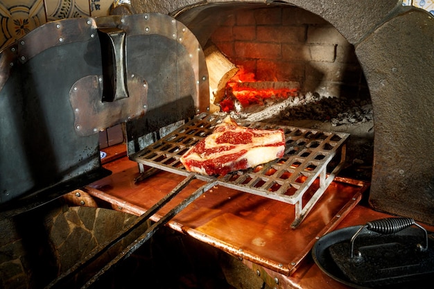 el chef pone el bistec mojado en el horno de piedra