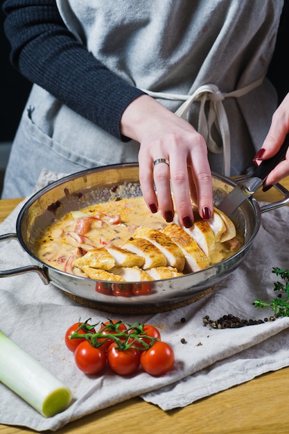 El chef pone las pechugas de pollo cortadas en la sartén.