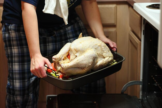 Foto el chef pone el plato de pollo en el horno.