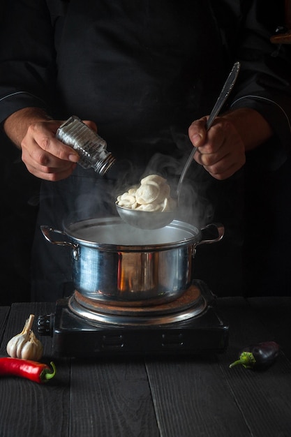 El chef prepara albóndigas en una cacerola en la cocina del restaurante Las manos del cocinero añaden sal