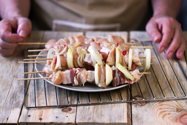 El chef prepara brochetas crudas sobre palitos de madera.