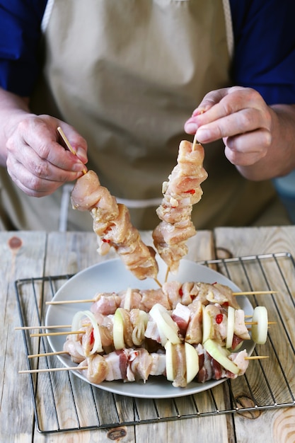 El chef prepara brochetas crudas sobre palitos de madera.