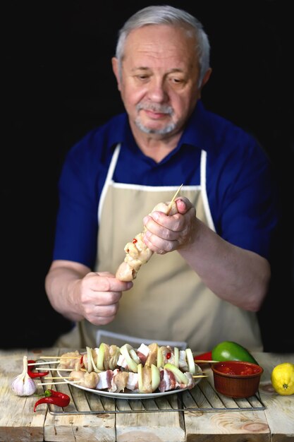 El chef prepara brochetas de pollo en palos de madera