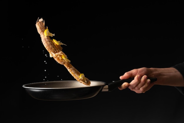 El chef prepara camarones mantis de marisco con limón Dilikates de la cocina de Asia oriental en un primer plano horizontal de la foto de fondo negro