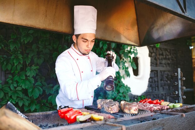 El chef prepara carne en la barbacoa.