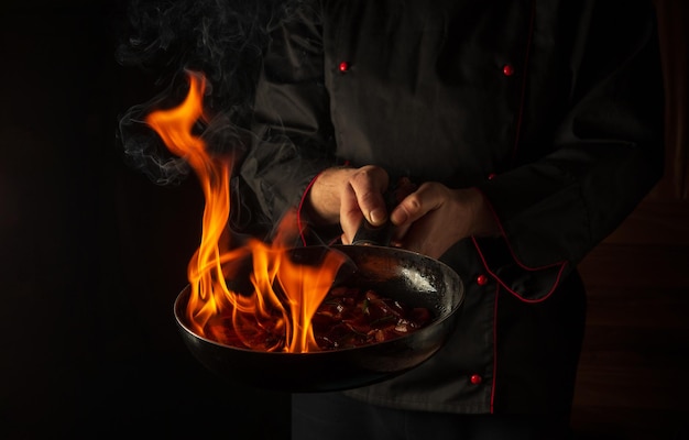 Chef prepara comida vegetal en una sartén con una llama de fuego