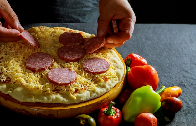 Chef prepara deliciosas pizzas, linguiça salgada, massa grossa, massa de pizza