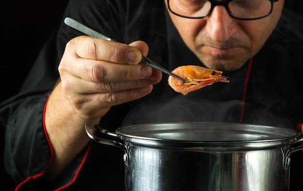 Un chef prepara deliciosos camarones en una olla en la cocina Delicious scampi o concepto de almuerzo de camarón para el hotel